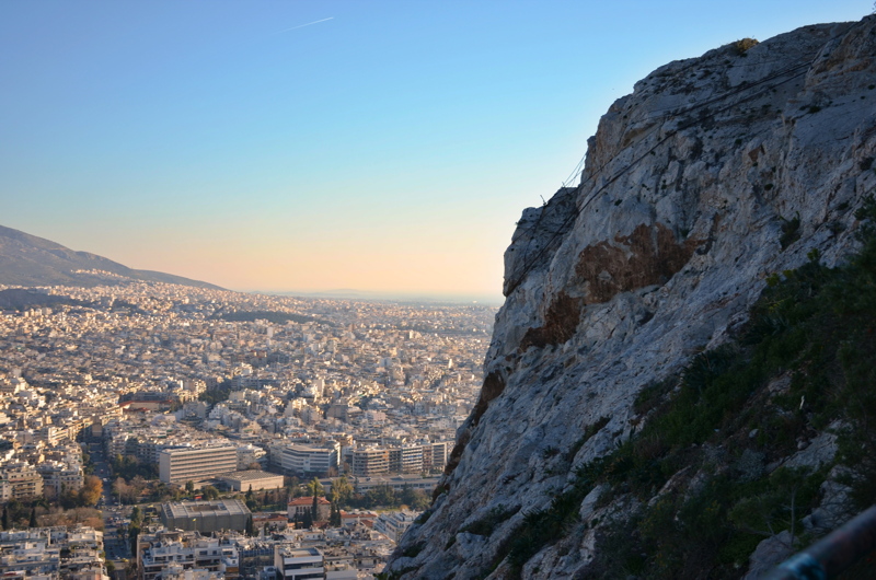 A scenic view overlooking the sprawling cityscape of Athens, Greece, captured from the rocky slopes of Mount Lycabettus
